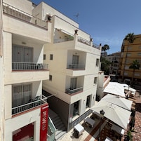 A multi-story building with balconies, outdoor seating, and a visible storefront.