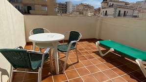 A terrace with a round table, two chairs, and a bench.