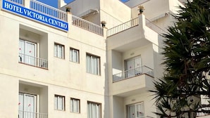 A multi-story hotel building with balconies, a sign for 'Hotel Victoria Centro,' and a 'FIRAM' restaurant entrance.