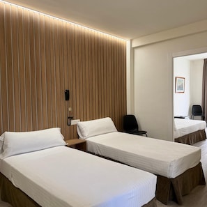 Una habitación de hotel con dos camas individuales, un panel de pared de madera, un teléfono y una silla.