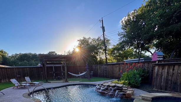A backyard with a swimming pool, a hammock, and a wooden fence. - Modern Backyard Paradise Pool & Spa Near Dallas (Farmers Branch)