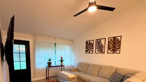 A living room with a sofa, coffee table, and a TV. - Modern Backyard Paradise Pool & Spa Near Dallas (Farmers Branch)