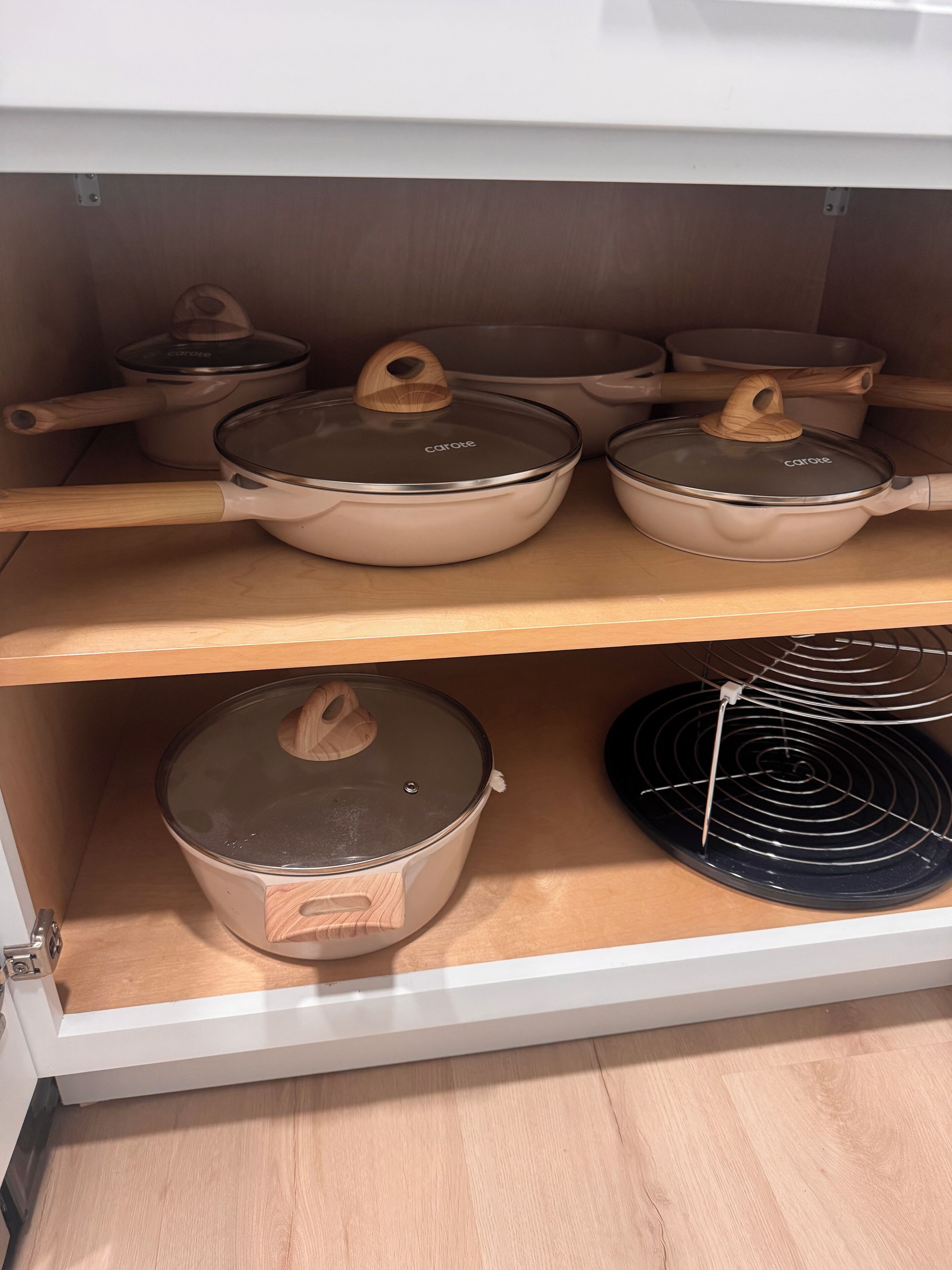 A kitchen cabinet with cookware, including pots and pans, and a black electric stove.