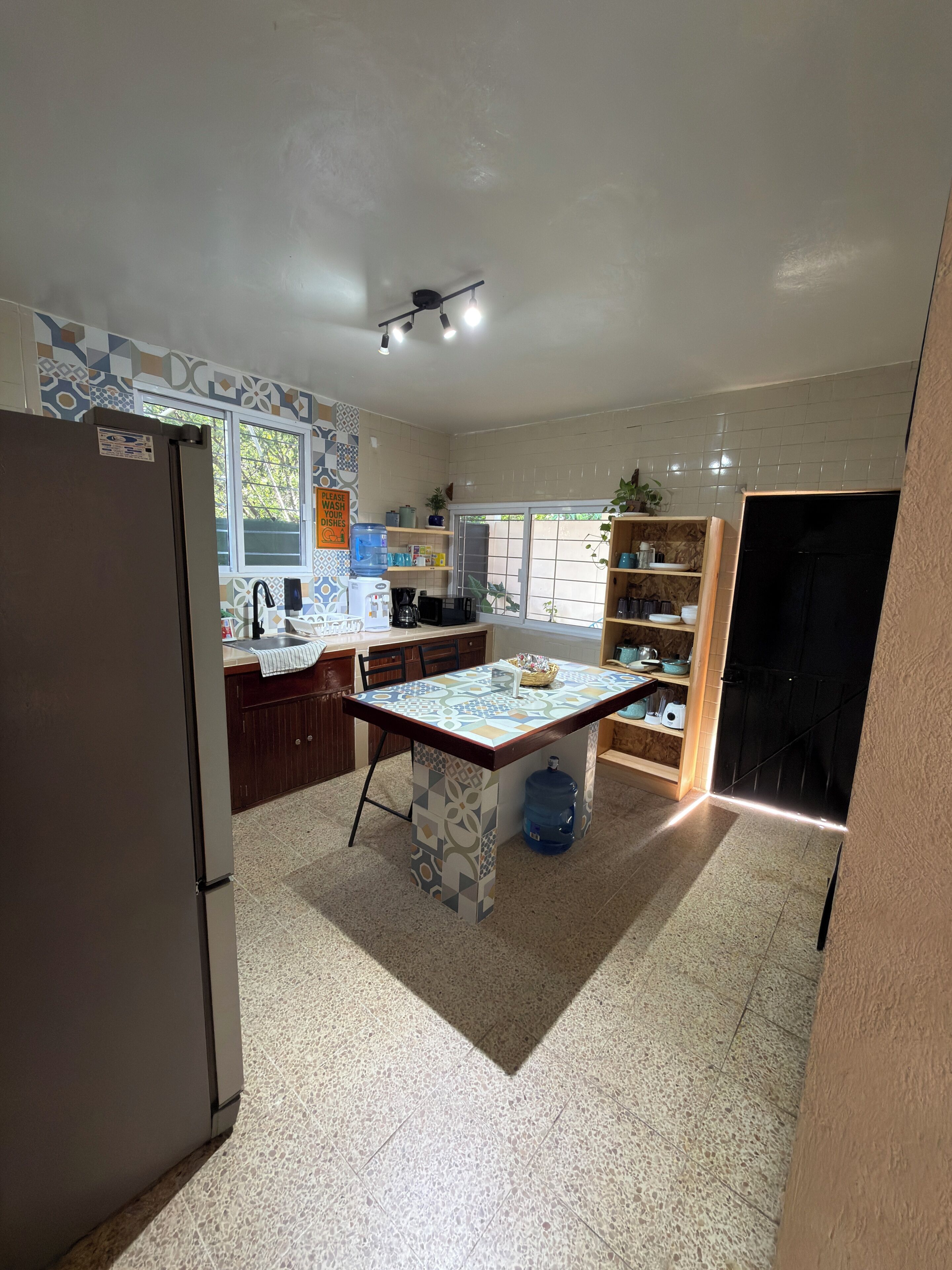 Una cocina con refrigerador, lavamanos, encimera y ventana.