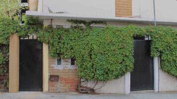 Un edificio con pared de ladrillo, dos puertas negras y un acceso cubierto.
