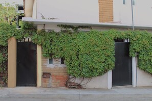 A building with a brick wall, two black doors, and a covered entrance.