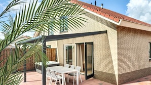 Un patio con tavolo e sedie, un edificio in mattoni con tetto in tegole e una palma.