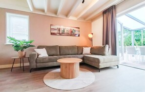 Ein Wohnzimmer mit Ecksofa, einem runden Couchtisch, einem Blumentopf und einem Bild an der Wand.