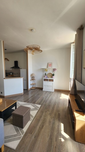 Un amplio espacio de estar con cocina, una mesa de comedor, un sofá y un televisor.