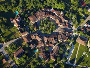An aerial view of a residential area with a circular layout of houses, a central roundabout, and a swimming pool.