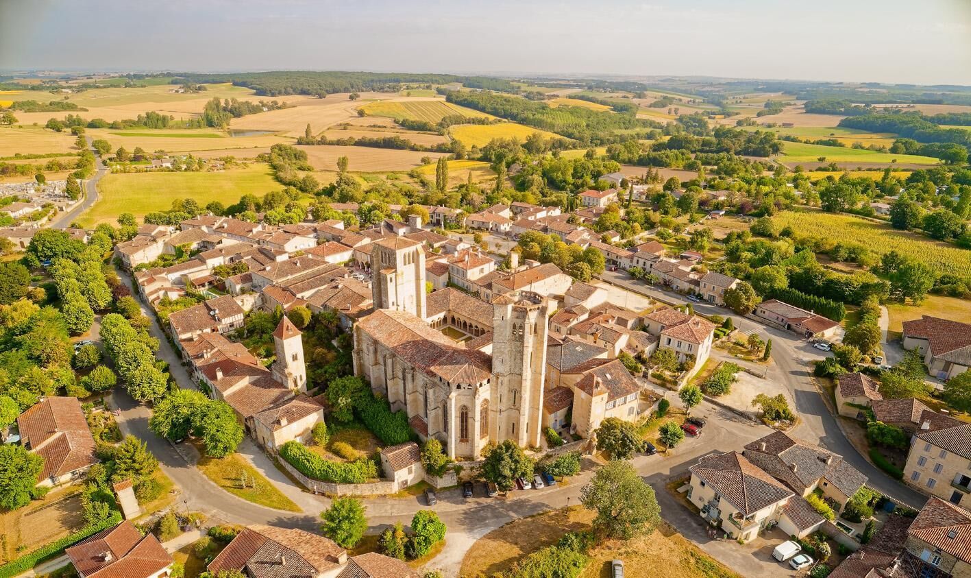 Luchtbeeld van een historische stad met een opvallende kerk, smalle straatjes en omliggende velden.
