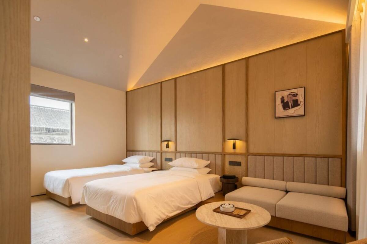 A hotel room with two beds, a sofa, a round table, and a window.