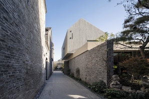 Un callejón estrecho bordeado por edificios de ladrillo y una estructura moderna con techo inclinado.