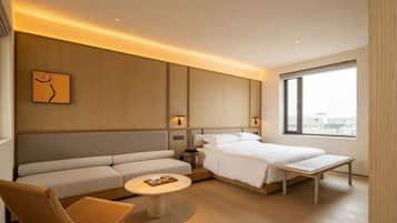 A modern hotel room with a bed, sofa, and a small table.
