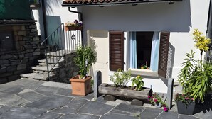 A stone-paved courtyard with a white building, wooden shutters, and potted plants. - Casa Cecilia Ascona 500m from the Lake, Ascona, Switzerland (Ascona)