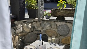 A stone wall, a table with a bottle of champagne, glasses, plates, cutlery, and a charcuterie board with meats and olives. - Casa Cecilia Ascona 500m from the Lake, Ascona, Switzerland (Ascona)