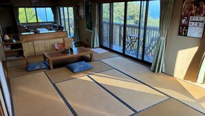 A tatami mat room with a wooden table, cushions, and a view of the outdoors.