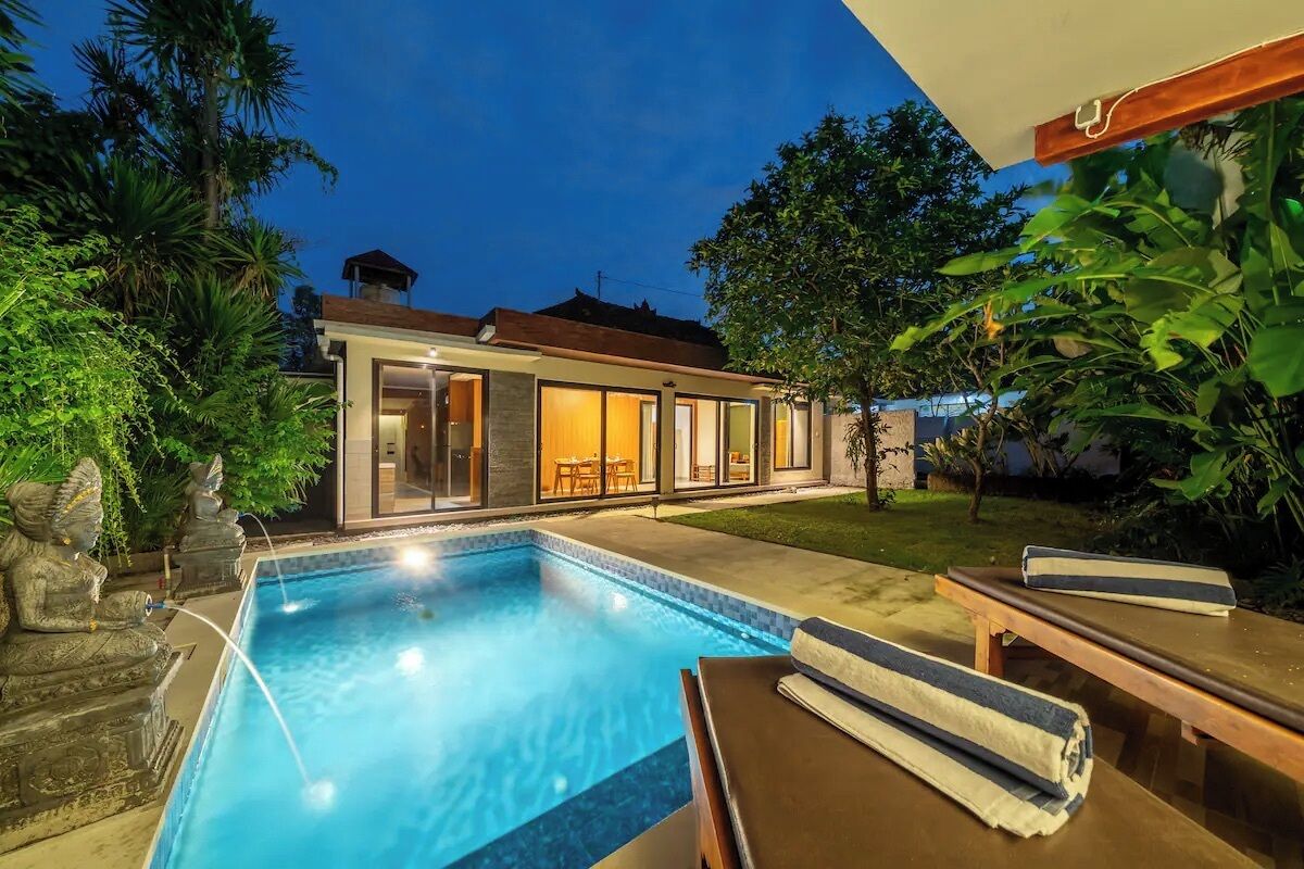 A modern house with a swimming pool, outdoor furniture, and lush greenery.