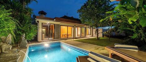 A modern house with a swimming pool, outdoor furniture, and lush greenery.