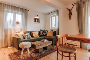Una sala de estar con sofá, mesa de centro y una mesa de comedor de madera.