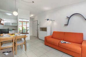 Ein stilvoller Wohnraum mit Essbereich, einem orangefarbenen Sofa und einer Küche.