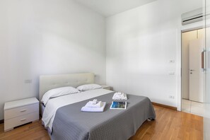 Ein Schlafzimmer mit Bett, Nachttisch, Kommode und Klimaanlage.