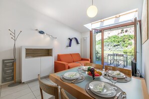 Ein Essbereich mit Tisch für vier Personen, einer Couch und Blick auf Grünflächen.