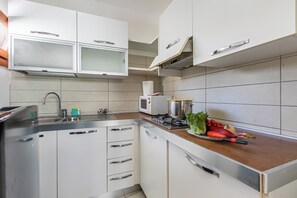 Eine moderne Küche mit weißen Schränken, Edelstahlgeräten und einer Holz Arbeitsplatte.