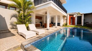 A modern poolside area with lounge chairs, a covered patio, and a clear blue pool. - Casa De Munggu (Tabanan)