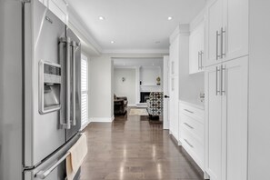 Une cuisine moderne avec des meubles blancs, un réfrigérateur en acier inoxydable et un tapis à motifs.