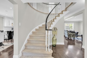 Ein modernes Interieur mit einer geschwungenen Treppe, einem Essbereich und einem Wohnzimmer.