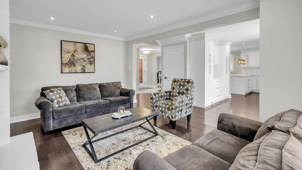 A modern living room with a grey sofa, patterned armchair, and coffee table. - Modern 4BR Family Home w/ Pool · Whitby (Whitby)