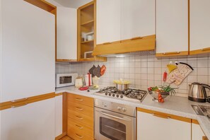 A kitchen with white cabinets, a stove, a microwave, and a kettle. - Kirribilli House, Nago-Torbole, Italy (Nago-Torbole)