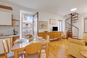Eine moderne Küche mit Essbereich, einem Fernseher und einer Wendeltreppe.