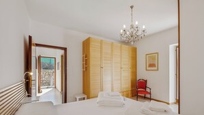 Een hotelkamer met een bed, een kroonluchter, een kledingkast en een rode stoel.