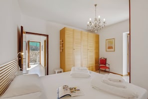 Ein Hotelzimmer mit Bett, einer Chandelierleuchtre, einem Kleiderschrank und einem roten Sessel.