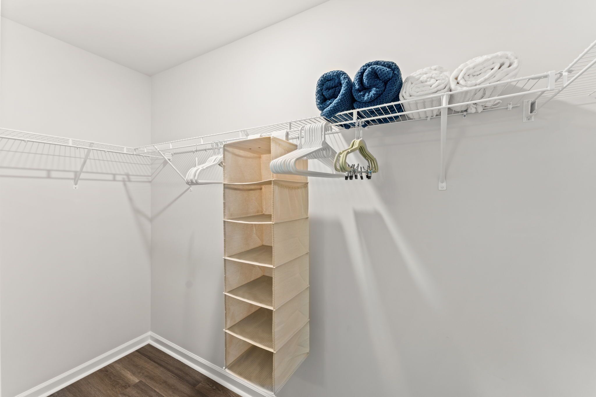 A white closet with a metal drying rack and shelves.