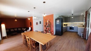 Eine moderne Küche mit Essbereich, Holzboden und Pendelleuchten.