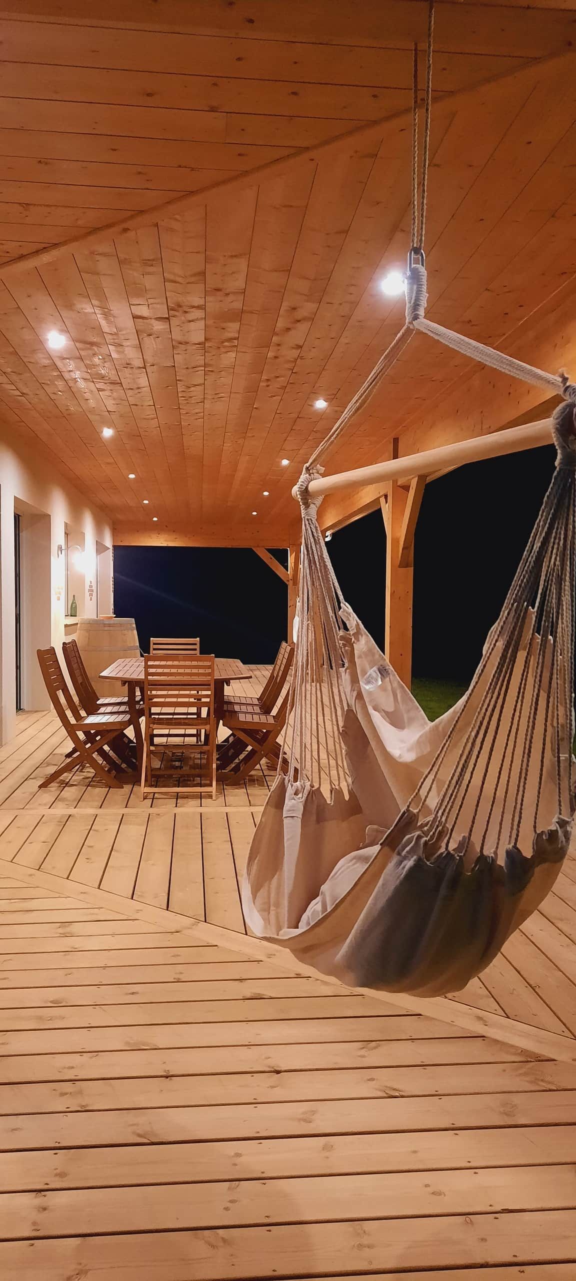 Une terrasse en bois avec une table et des chaises, ainsi que deux hamacs.