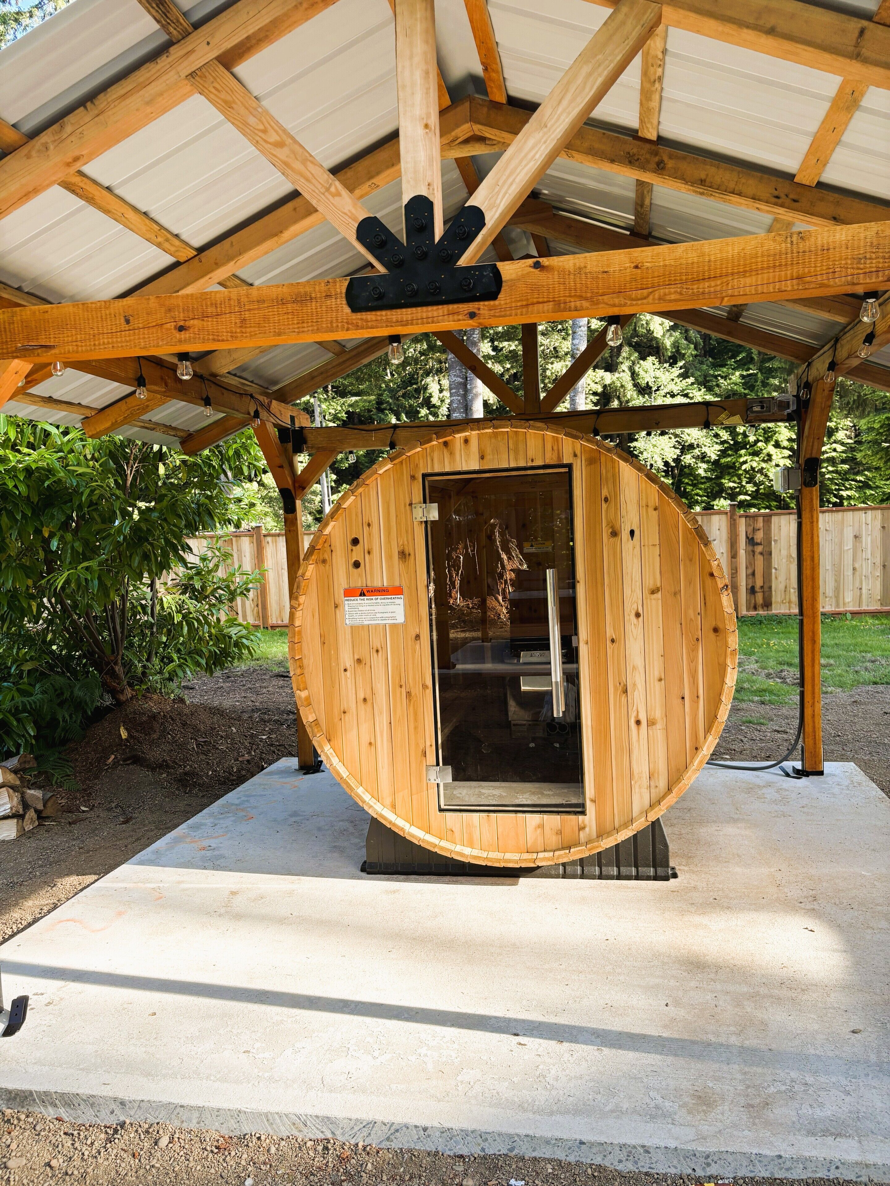 Una sauna de fusta amb teulada metàl·lica, una porta i un senyal de perill.