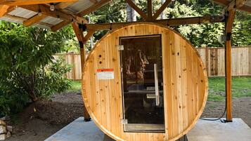 A wooden sauna structure with a metal roof, a door, and a warning sign.