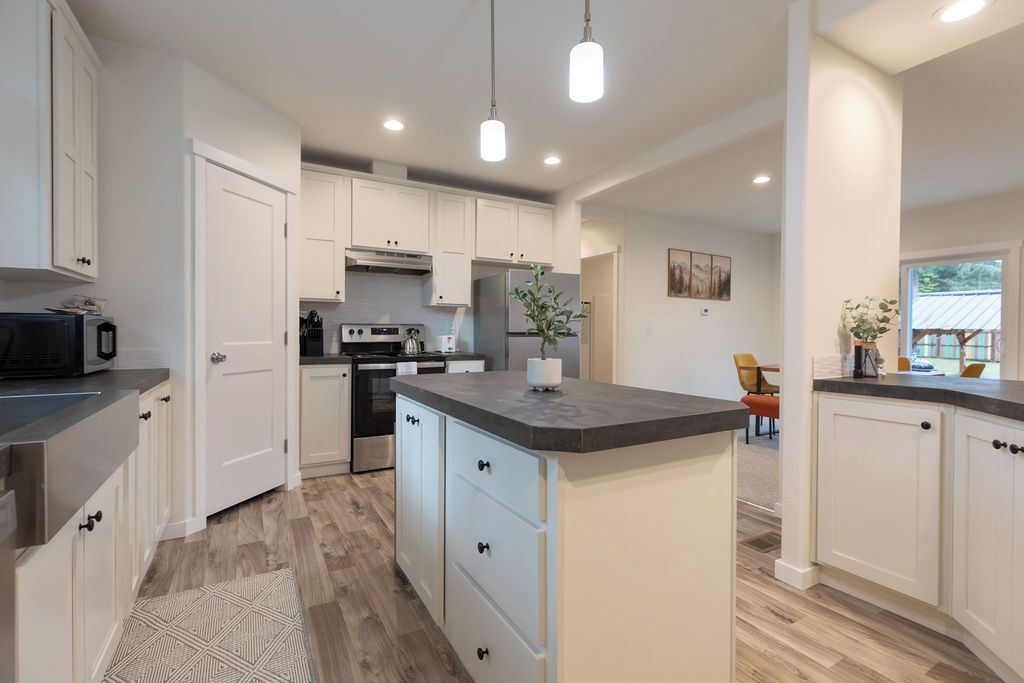 A modern kitchen with white cabinetry, a central island, and built-in appliances.