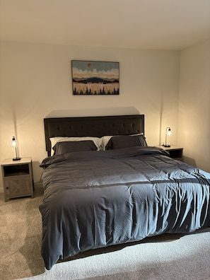 Un dormitorio con una cama grande, dos mesitas de noche, un cuadro colgado en la pared y una lámpara de pie.