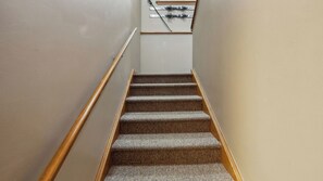 A carpeted staircase with wooden handrails, leading to a landing with a white wall and a ski rack. - Open Pit by Avantstay Indoor Heated Pool + Rec Center Near Gore + Hudson (North Creek)