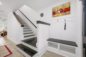 A staircase with a handrail, a wall-mounted clock, a painting, and a built-in bench. - Near Med Center and NRG Stadium, Game Room, Fireplace (Houston)