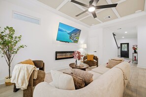 A living room with a fireplace, a television, and a ceiling fan. - Near Med Center and NRG Stadium, Game Room, Fireplace (Houston)