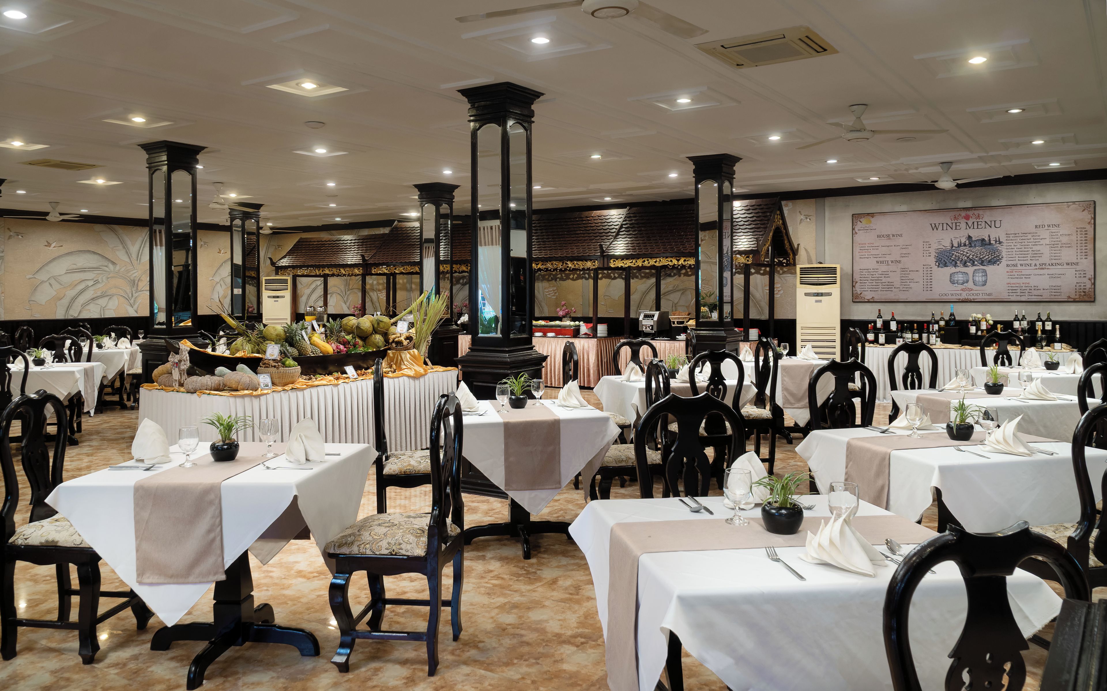 A restaurant with multiple tables set for dining, a wine menu on the wall, and a decorative wall with a mural.
