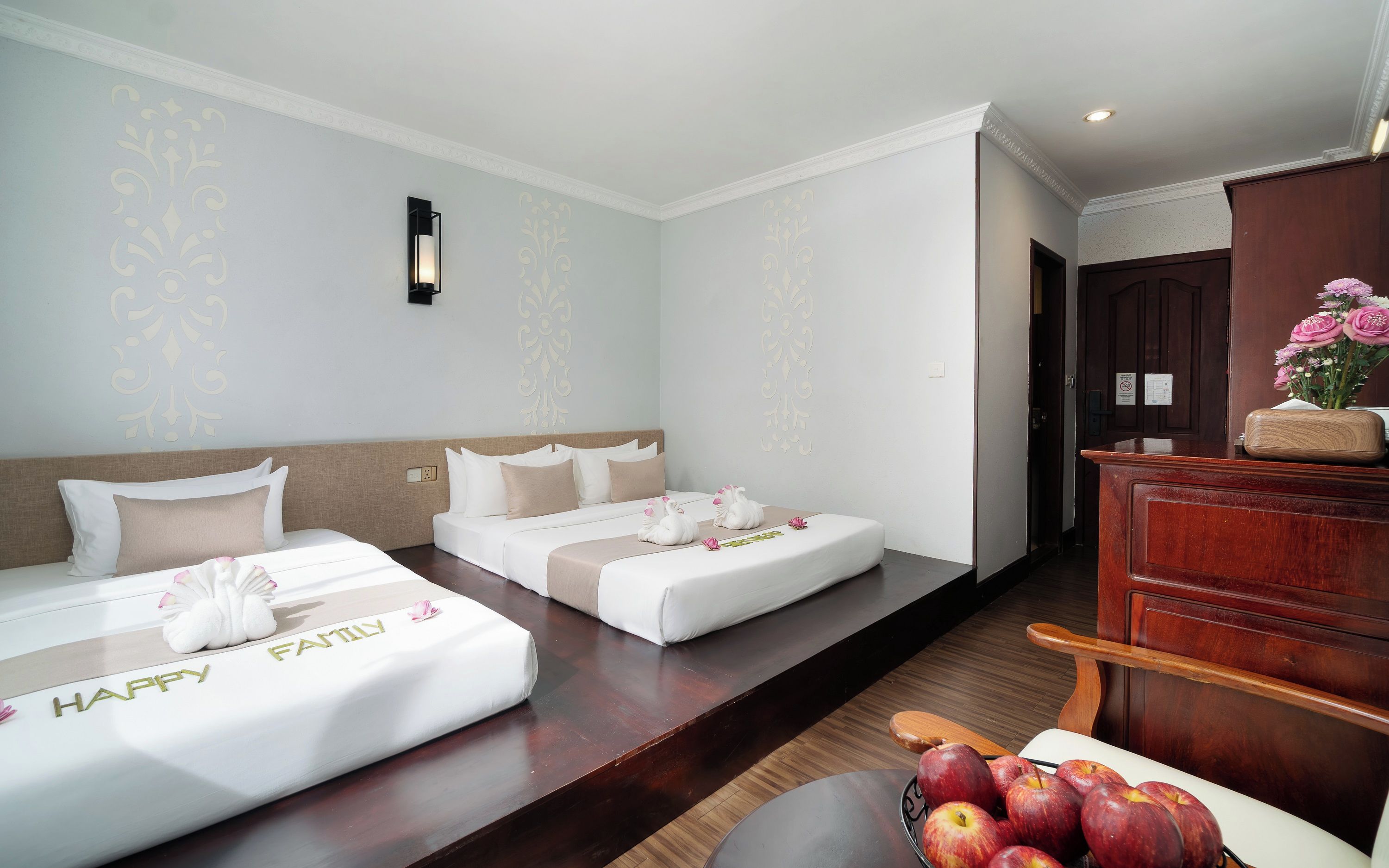 Habitación de hotel con dos camas, un aparador de madera y un frutero.