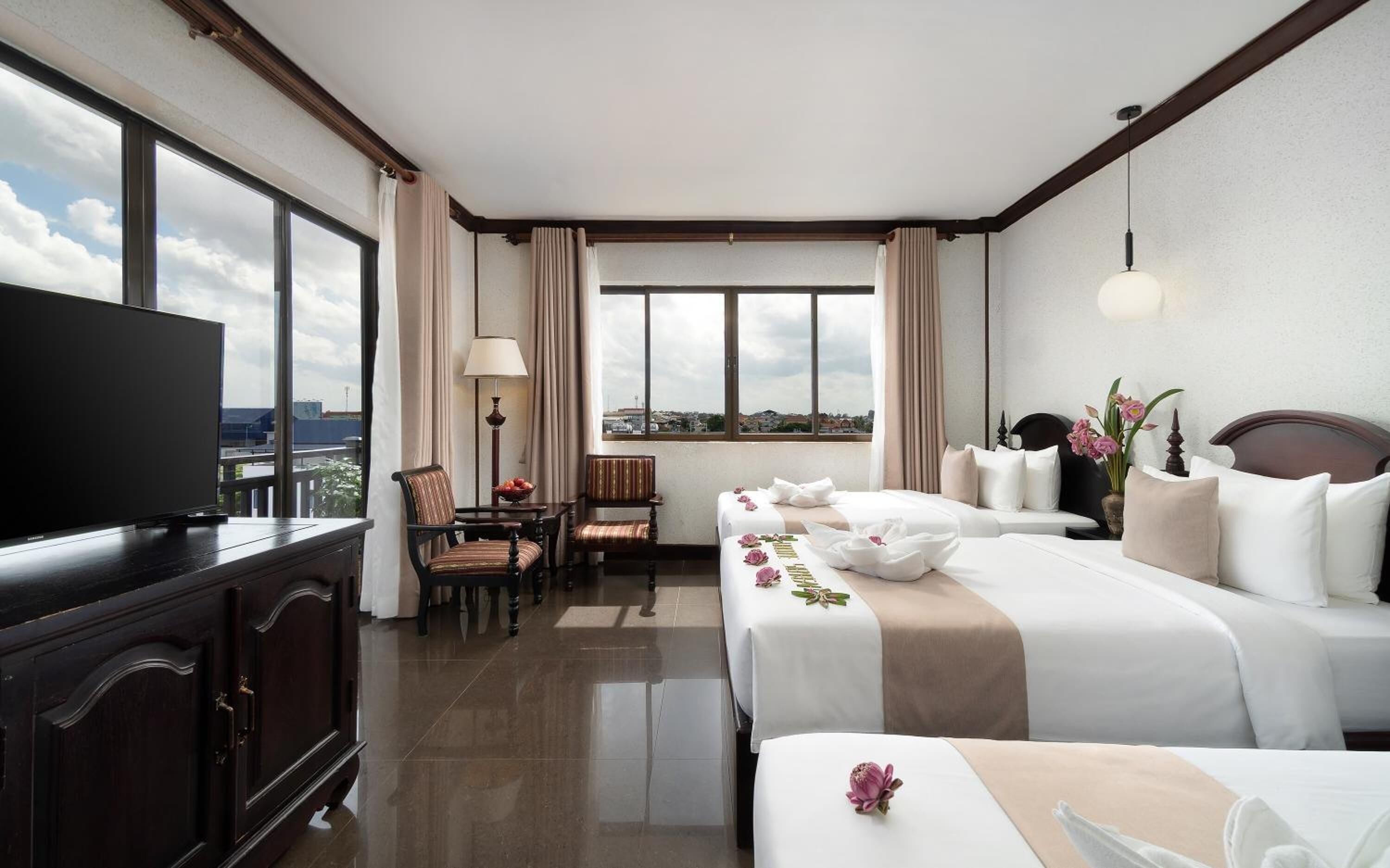 Une chambre d’hôtel équipée d’une télévision, de deux lits, d’un bureau et d’une chaise.