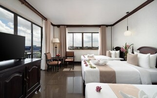 A hotel room with a television, two beds, a desk, and a chair.